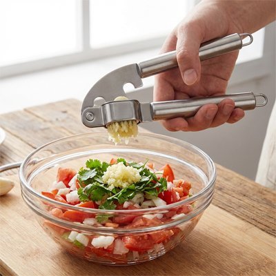 Presse‑ail écrasant des gousses pour aromatiser de la tomate et du celéries haché 