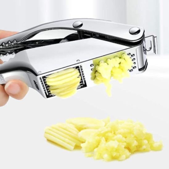 Presse‑ail manuel en inox avec gousses d’ail prêtes à être écrasées.