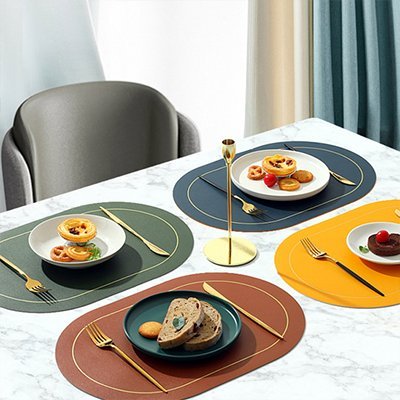 Set de table moderne en tissu coloré avec assiette et couverts dorés sur une table en marbre