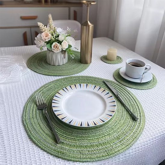 Set de table rond vert placé sous une assiette blanche.