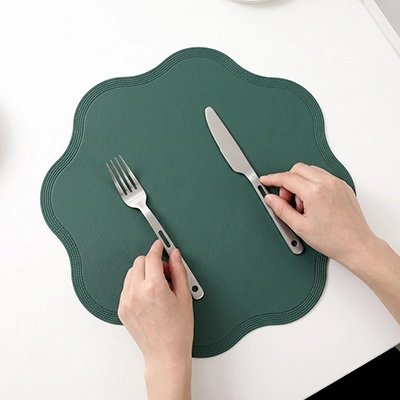Set de table vert en forme ondulée servant de base à un couvert élégant