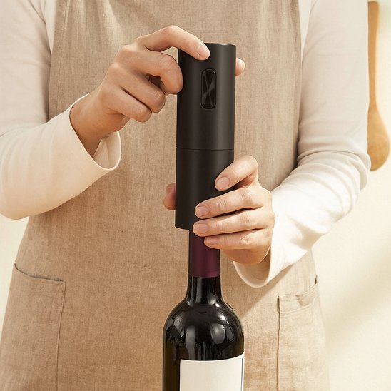 Tire bouchon électrique débouchant une bouteille de vin dans une cuisine éclairée